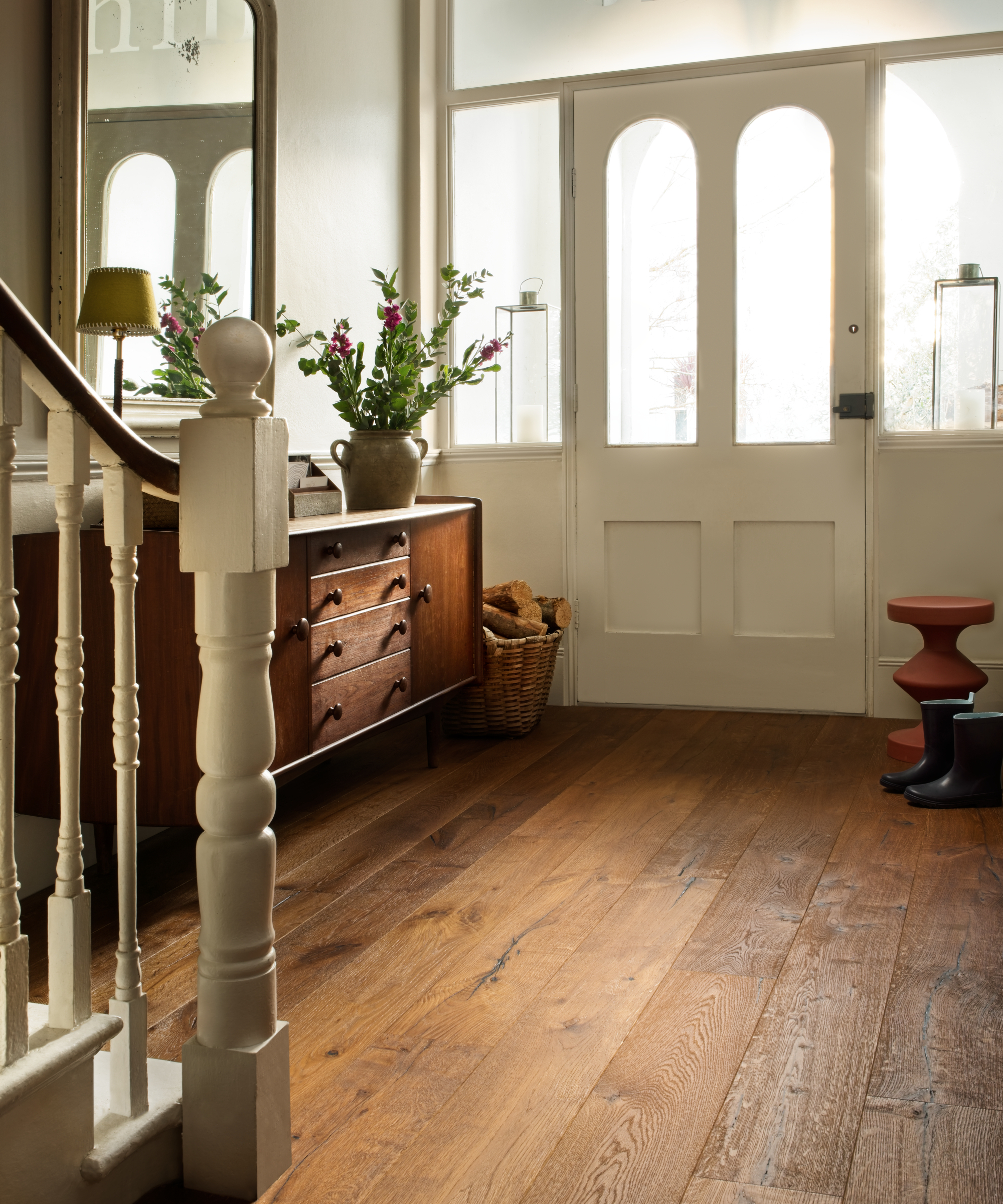 cream front door with arched glazed top section, glazed upper sections to side, wooden hallway flooring and cream painted stairs