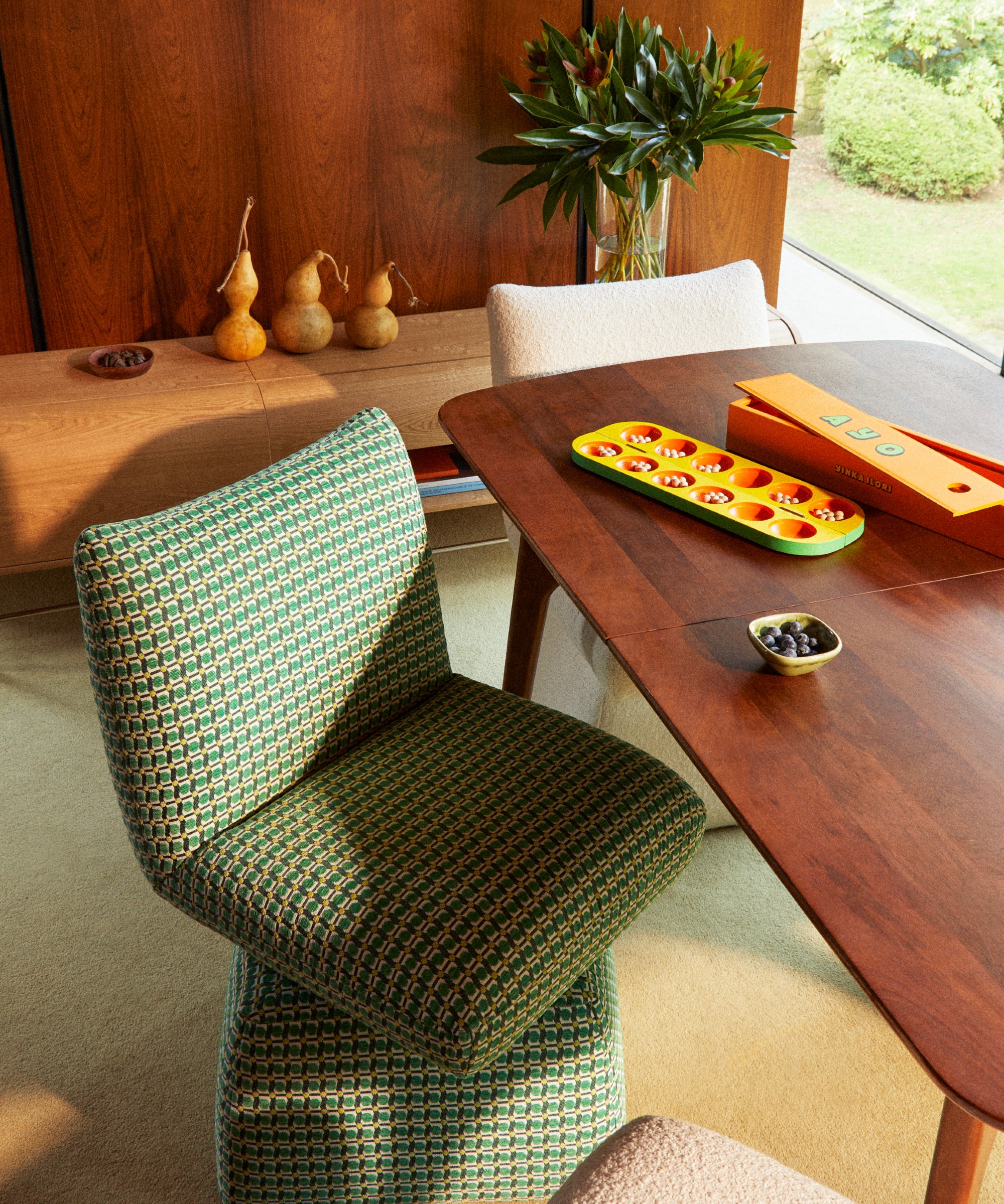 A dining room with upholstered swivel dining chairs from the Dunelm x Yinka Ilori collection and the sideboard from the range in the background