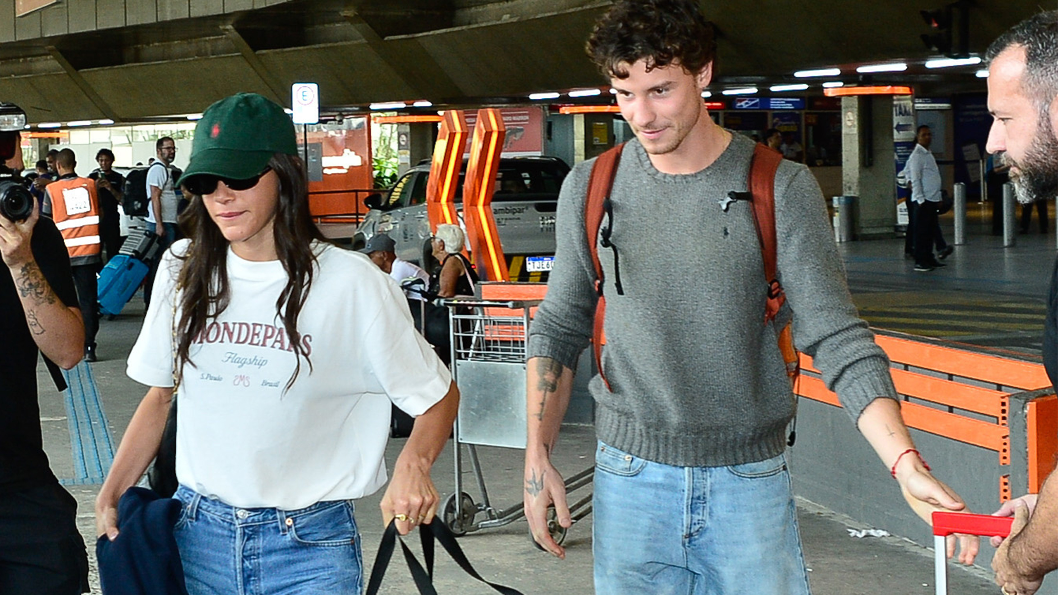 Bruna Marquezine and Shawn Mendes spotted at the S&atilde;o Paulo airport together. Marquezine is wearing a graphic T-shirt, green Polo hat, jeans, and red sneakers. She's carrying a dog carrier. 