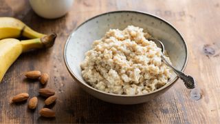 Porridge plain in bowl next to a couple of bananas on the side