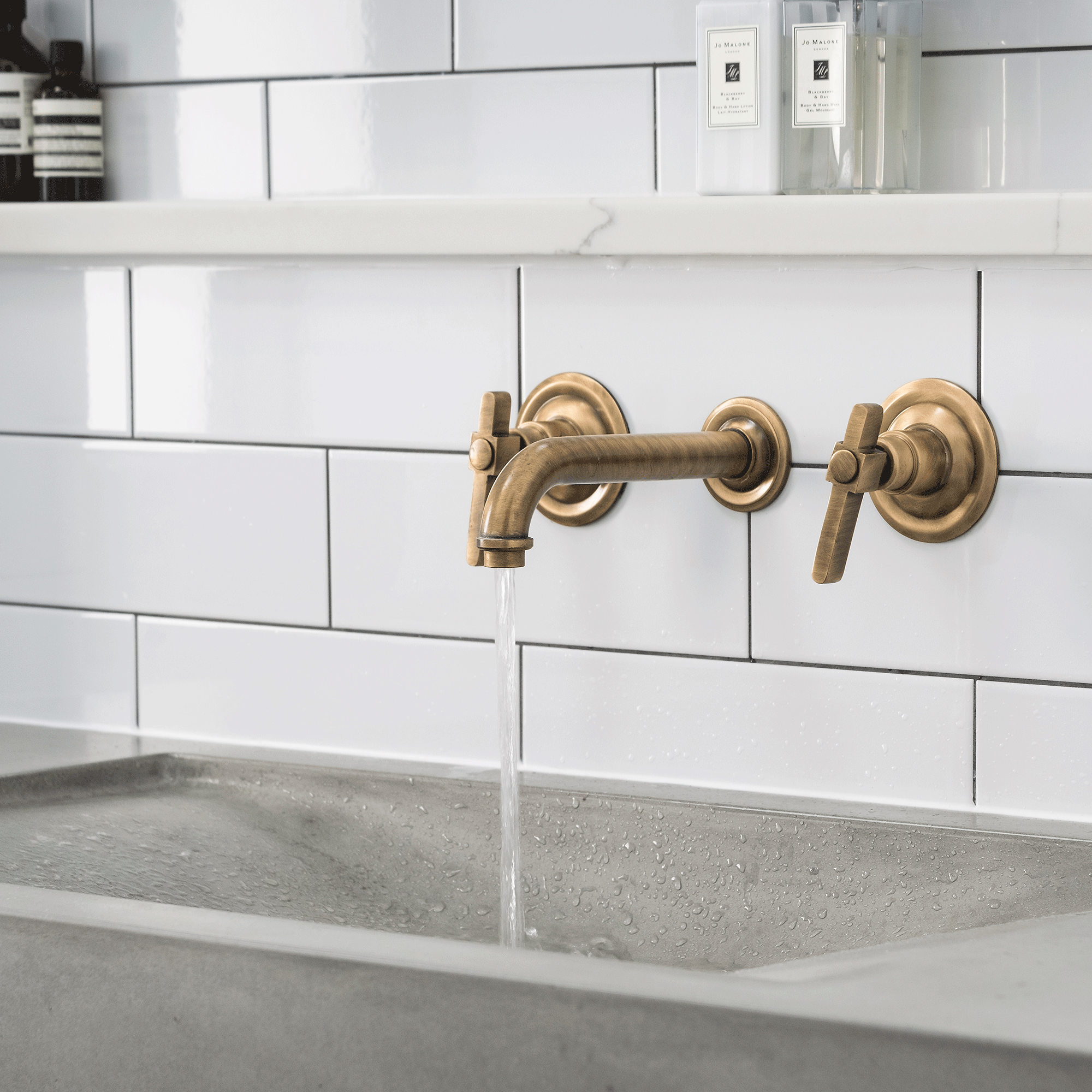 Concrete sink with white tiles and gold taps