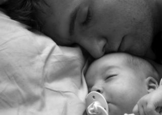 A father sleeps with his baby.