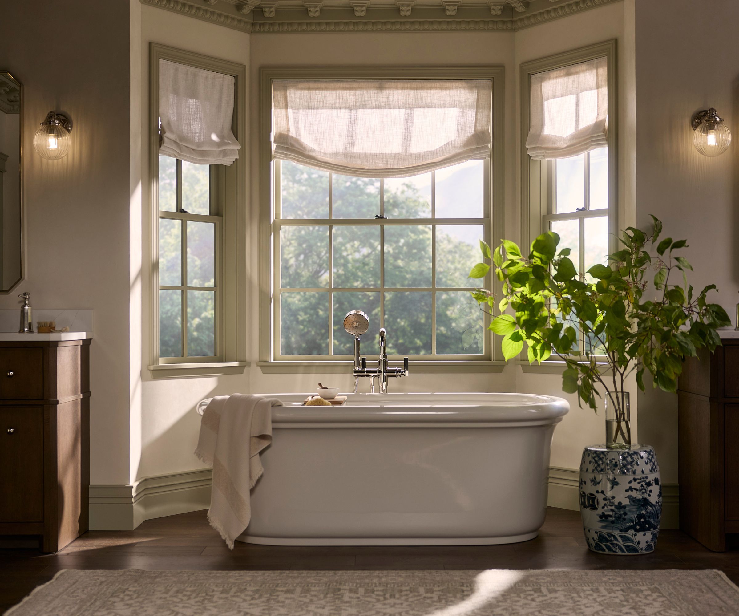 A large neutral bathroom with a bath in a bay window