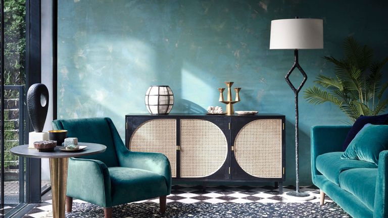 Cosy Coco设计的蓝绿色客厅，天鹅绒沙发家具，大理石方格地板，藤条橱柜，白色灯罩落地灯