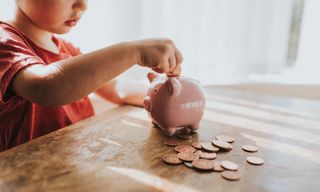 Child putting coins in a piggy bank