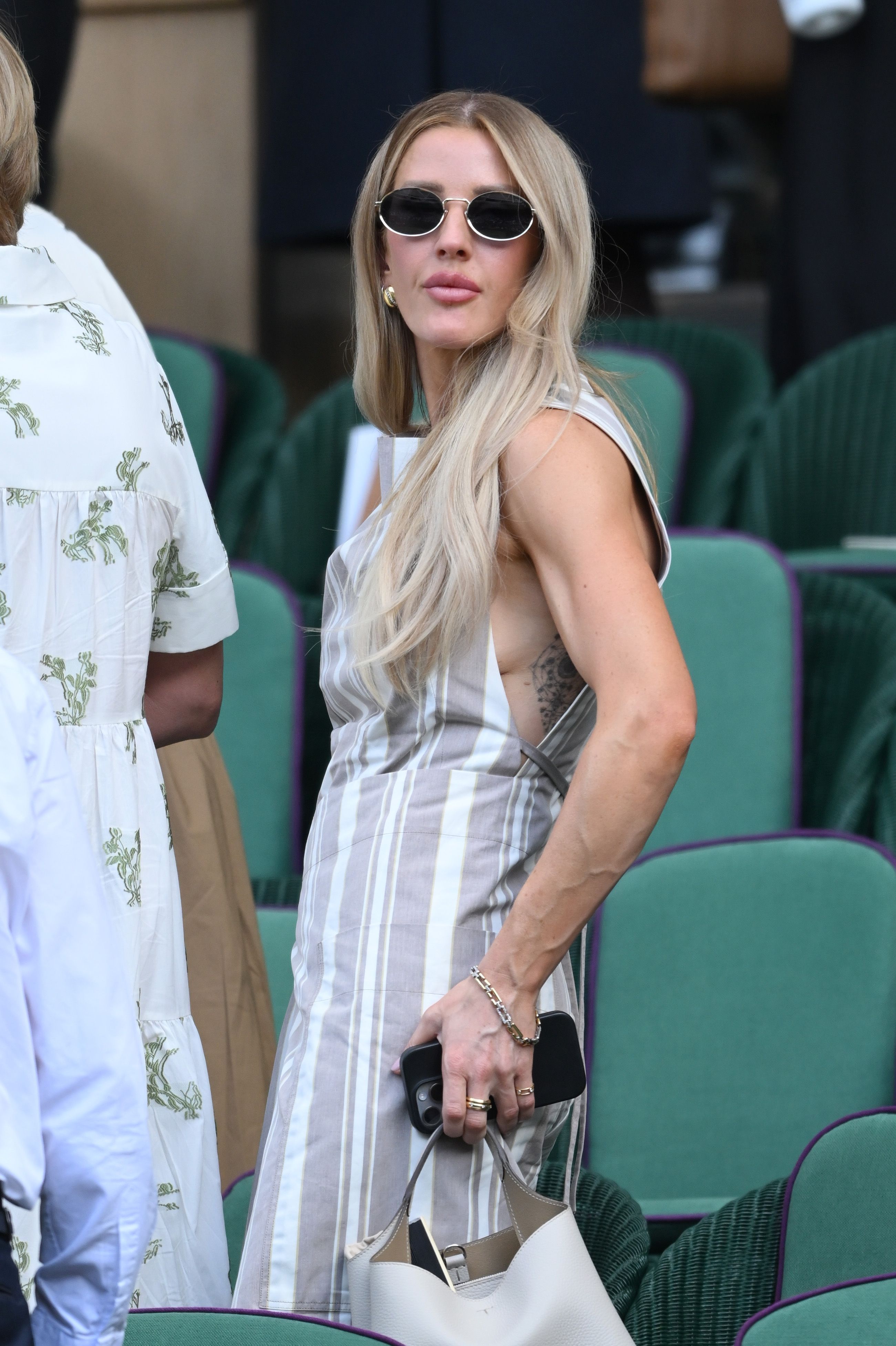 Ellie Goulding wears a striped linen dress and top handle bag at Wimbledon