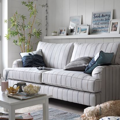 living area with white wall and grey sofa set with snacks on white teapoy 