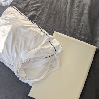 The Emma Original Hybrid Pillow being tested on a bed with a grey linen duvet cover