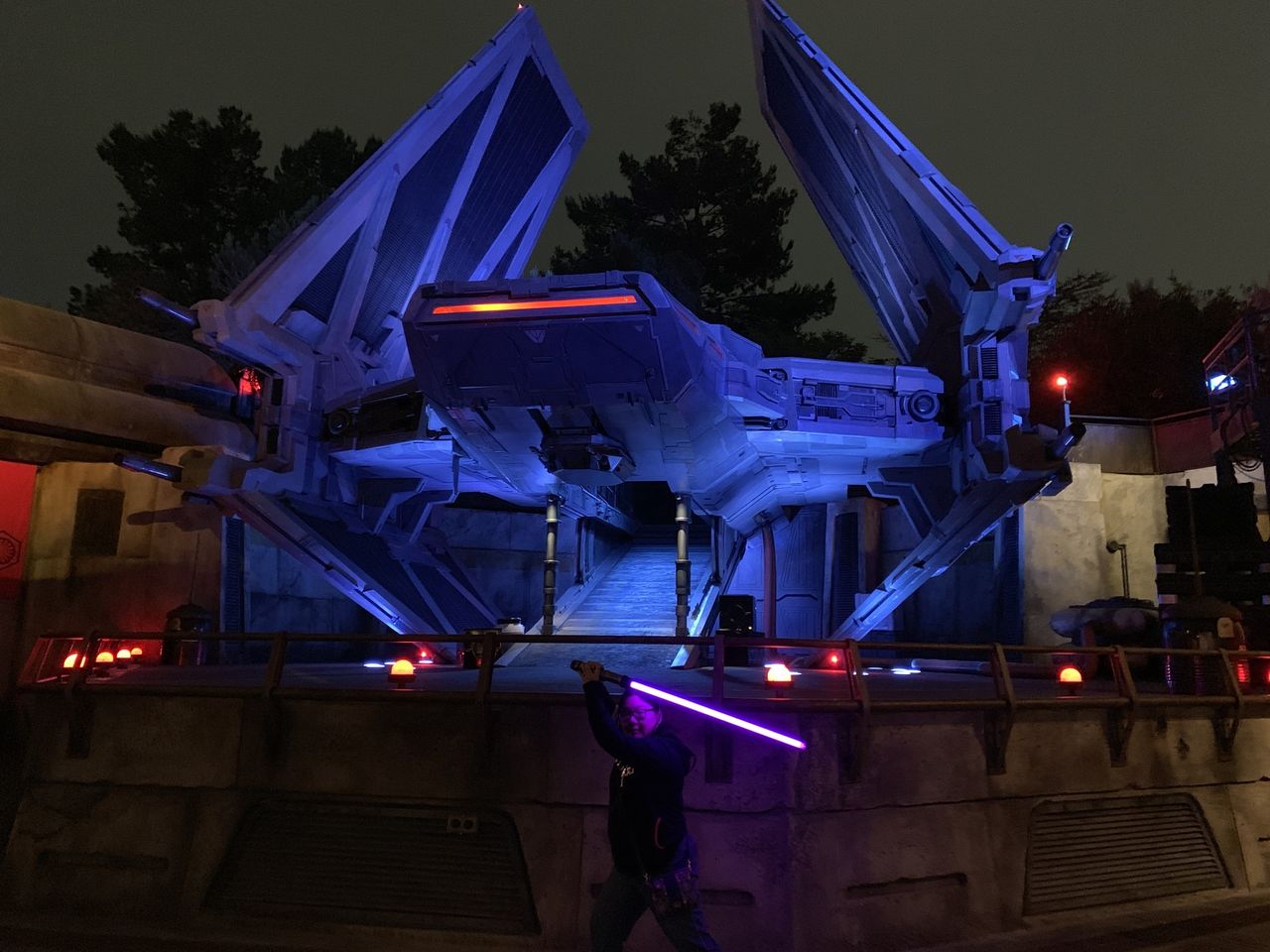 Christine posing with lightsaber in front of Kylo Ren's tie fighter