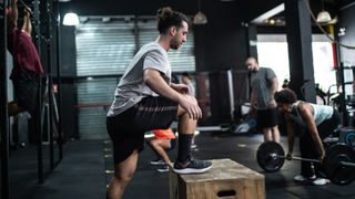 Man works his glutes out performing a step-up at the gym
