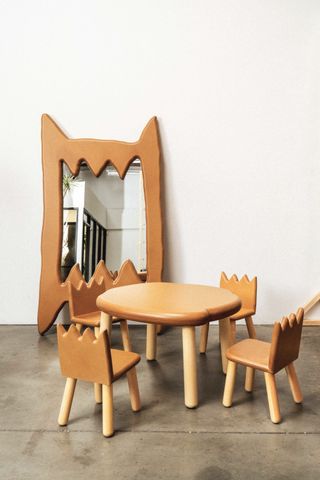 A cartoony table set with four chairs and a large-scale mirror feature a play-dough like, brown finish and zigzag lines.