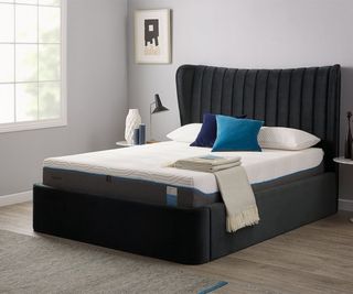 TEMPUR-Cloud Mattress on a bed with blue pillows against a gray wall.