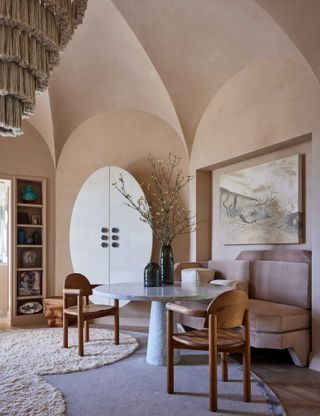 dining room with high domed ceiling, pink walls, marble round table