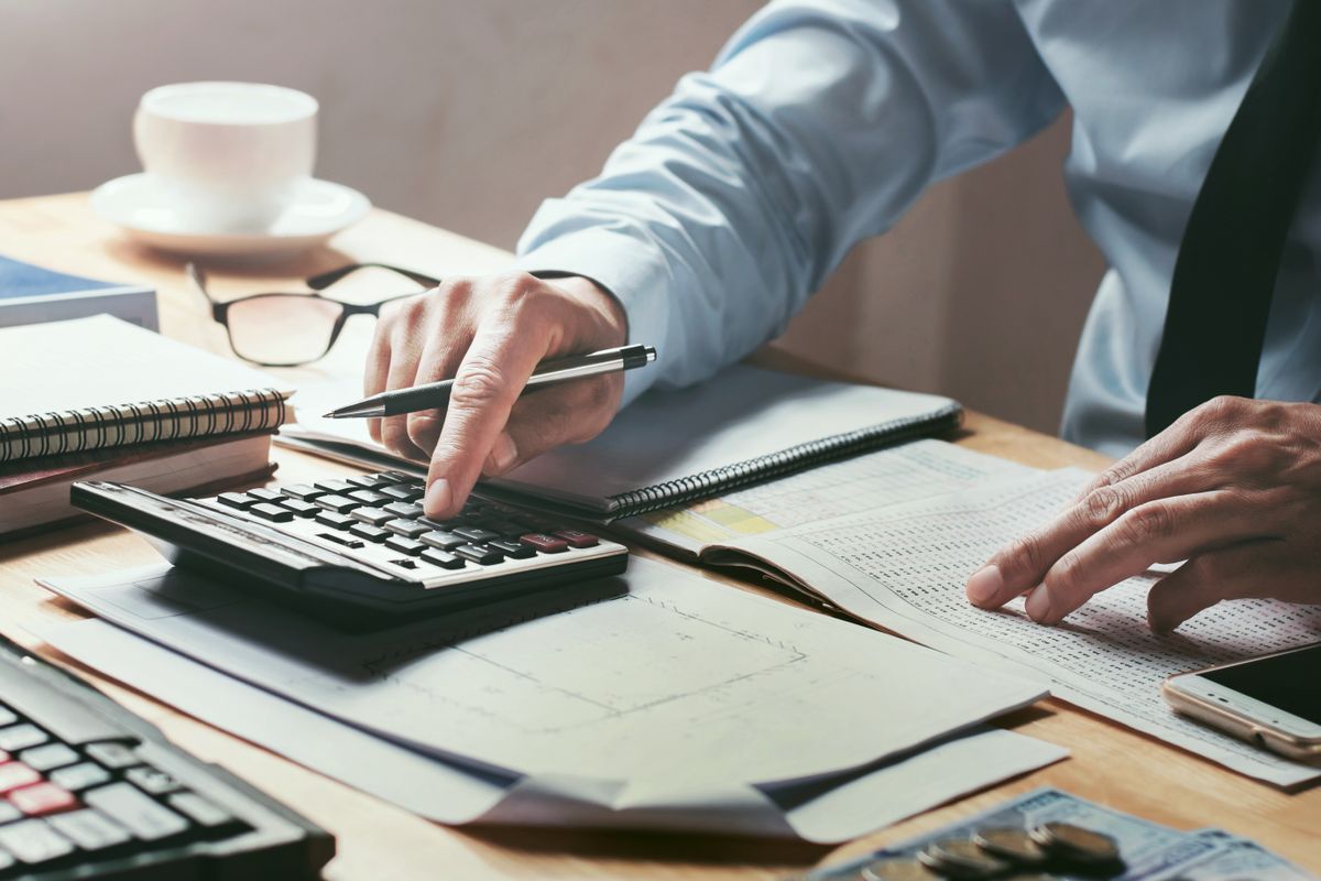 Business man entering numbers into a calculator on their desk, looking busy