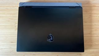 MSI Titan 18 HX gaming laptop with lid closed showing matte black surface and silver rear shelf on a wooden desk