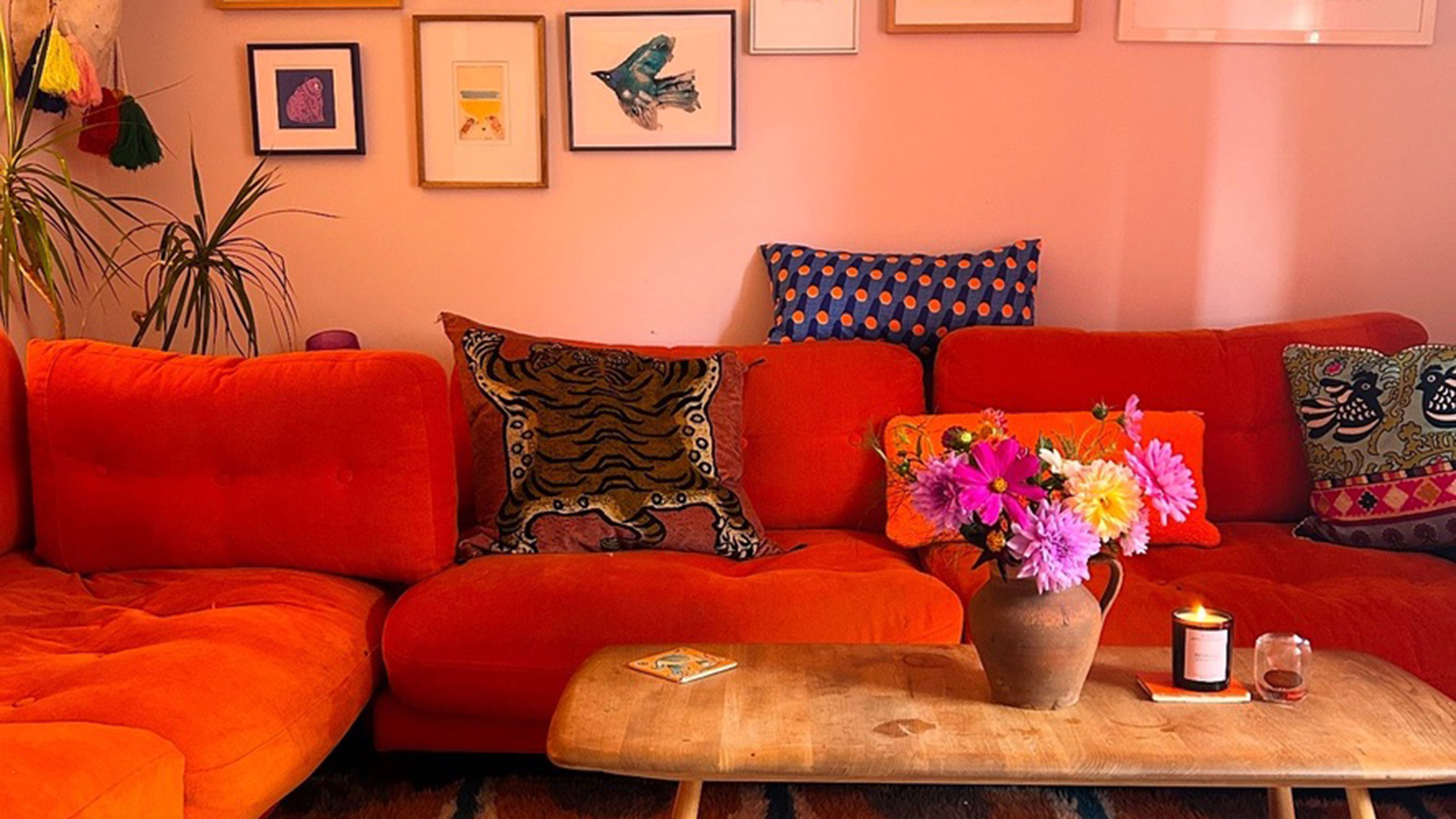 Pink living room with orange sofa and colourful flowers on coffee table