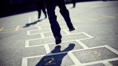 A boy plays hopscotch on a playground