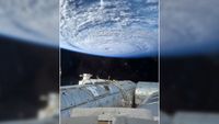 a white swirl of cloud above blue ocean waters as seen from space