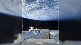 a white swirl of cloud above blue ocean waters as seen from space