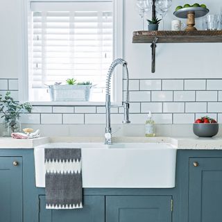 blue kitchen with white subway tile splashback and oversized butler sink