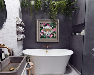 A waterpoof painting of a tiger hung above a bathtub in a charcoal grey bathroom