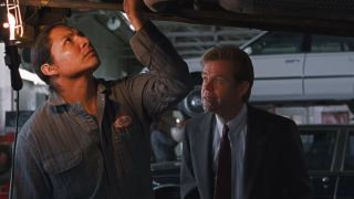 Steve Reevis looking up at the underside of a car, talking to William H. Macy in Fargo