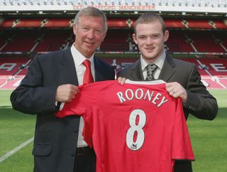 Wayne Rooney poses with Sir Alex Ferguson at Old Trafford after signing for Manchester United in 2004.