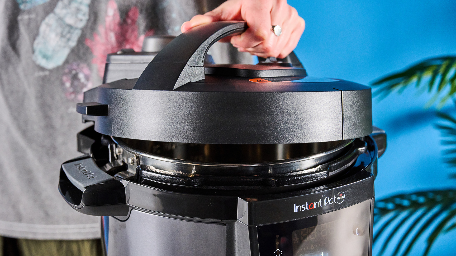 Instant Pot Plus photographed in front of a blue background.