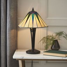 Dark Star Tiffany Lamp on a marble top side table, next to a green book and house plant.