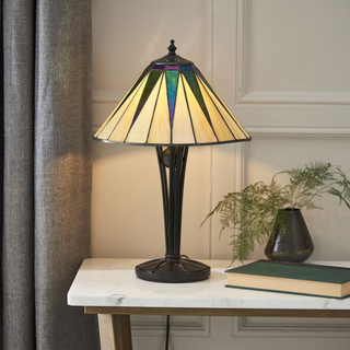 Dark Star Tiffany Lamp on a marble top side table, next to a green book and house plant.