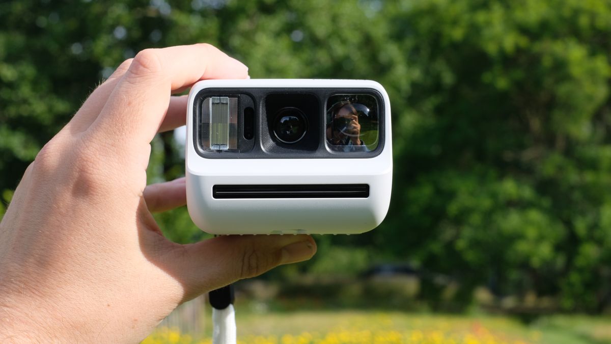 Photograph of man's hand holding Polaroid Go Gen 3 camera in white
