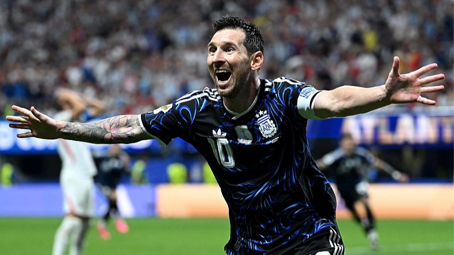Lionel Messi, wearing dark blue and with his arms outstretched, celebrates Argentina beating England at the World Cup 2026