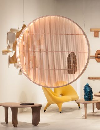 A spherical, two-dimensional lamp shade hangs from the ceiling in a futuristic furniture-filled gallery.