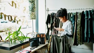 Smiling woman checking smartphone while shopping in boutique shop