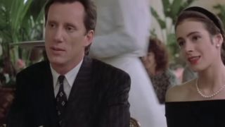 James Woods in a suit, sitting at a table next to a woman in The Boost.