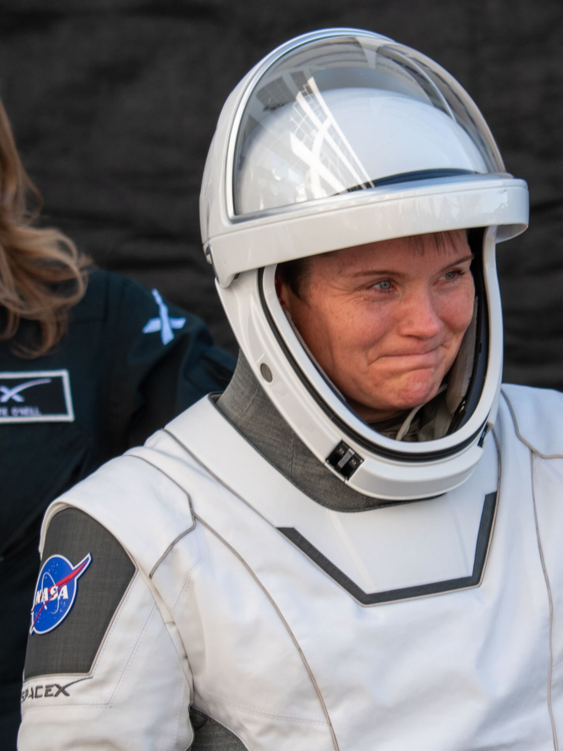 astronauts walk out of a building and board black cars.