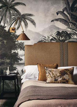 A bed with a mural on the behind behind and a fabric headboard