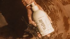 White bottle of body wash in rock stream