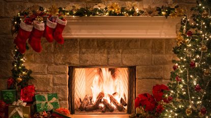 Ideas for stocking stuffers: Four stockings hung by a fireplace with Christmas decorations around it