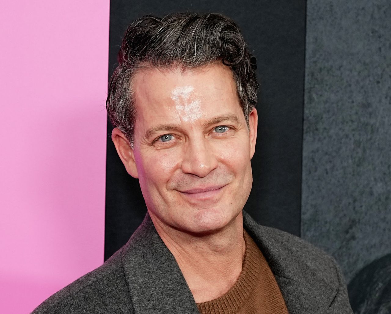 A headshot of a man with dark hair smiling at the camera