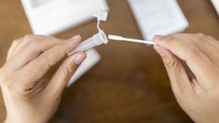 A man places a long cotton swab inside of a plastic test tube