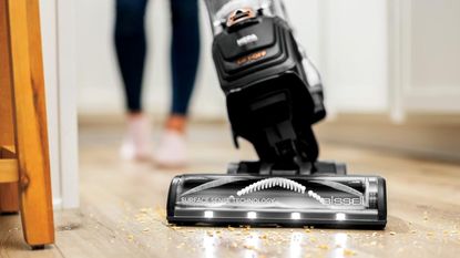 Bissell SurfaceSense Allergen Pet Lift-Off Upright Vacuum vacuuming debris on wooden floor