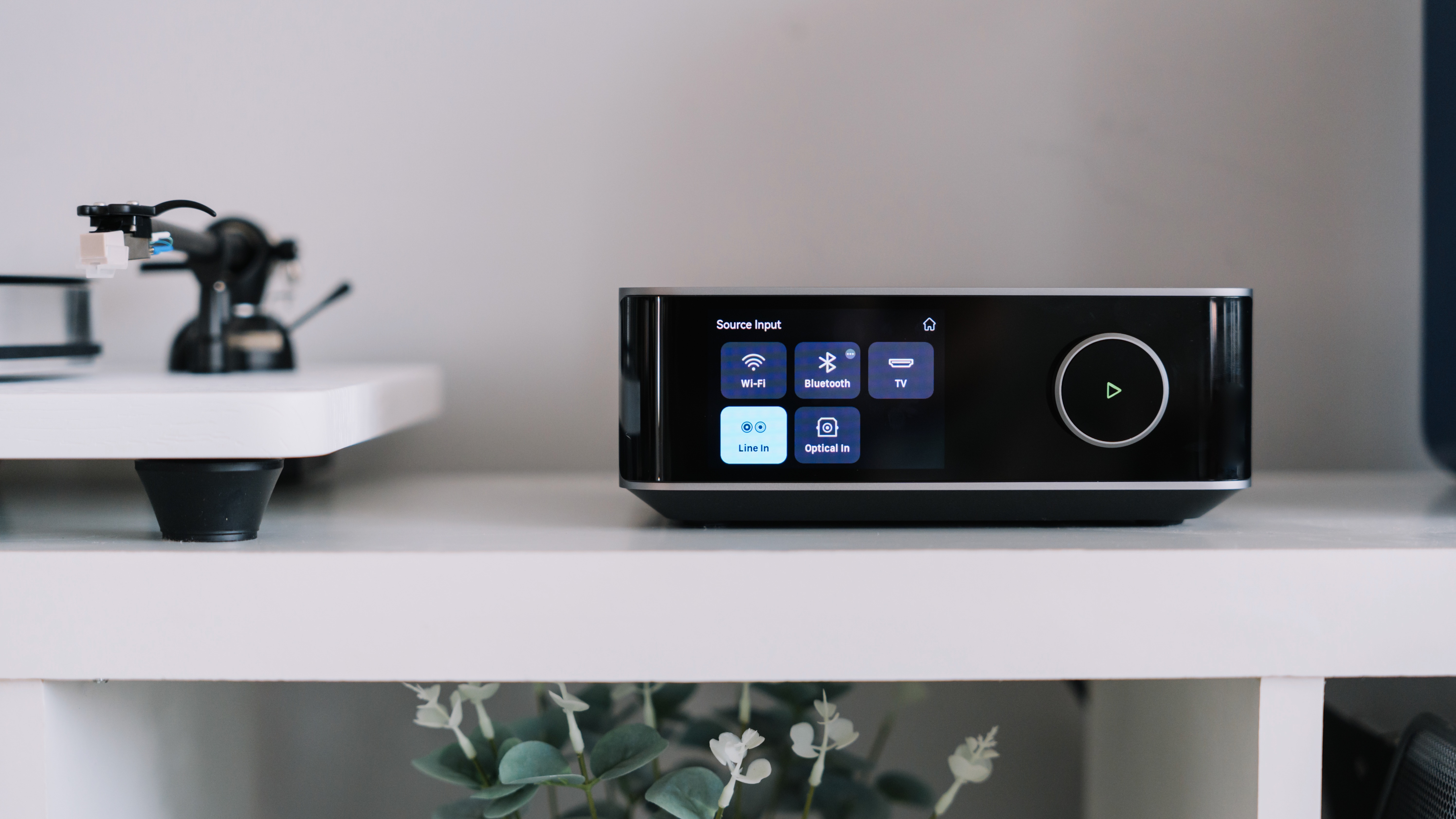WiiM Amp Ultra on white shelf next to a turntable