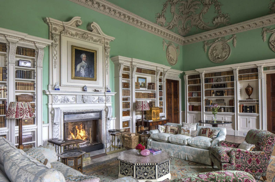 interior view of kitlington park, showing the richly detailed library room, with fine plasterwork and a roaring fire