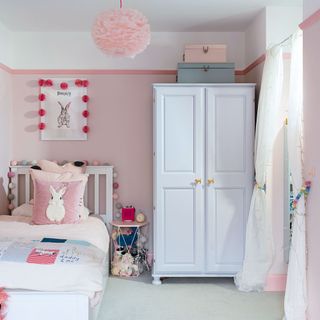 pink girls bedroom with white bed and wardrobe