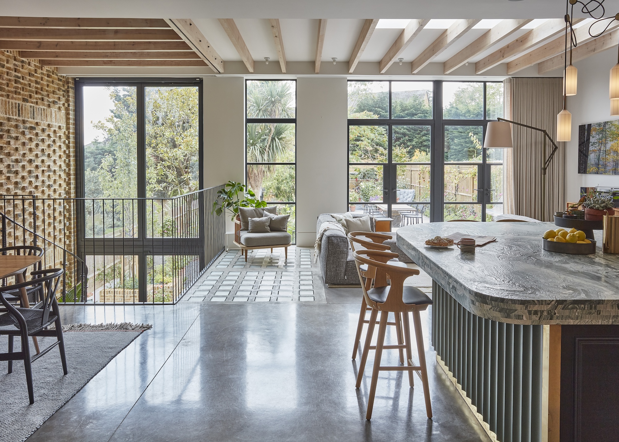 An open plan kitchen with a curved island in the middle and bar stools
