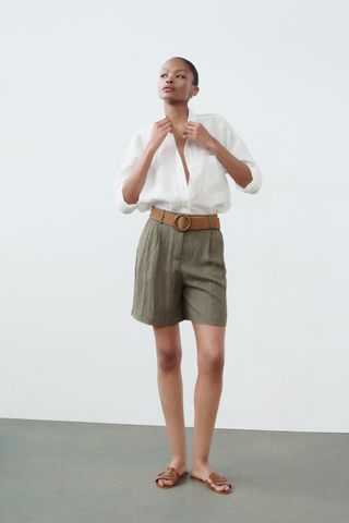 model wears a white shirt and long olive green shorts 