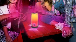 JBL Pulse 5 on table with LED lights amidst a group at a table.