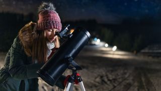 Woman studying the night sky using one of the best budget telescopes