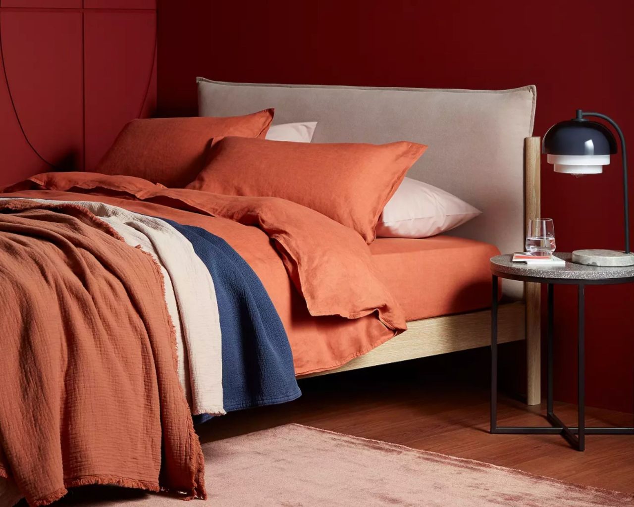 John Lewis &amp; Partners Pillow Bed Frame inside red room with colourful bedding
